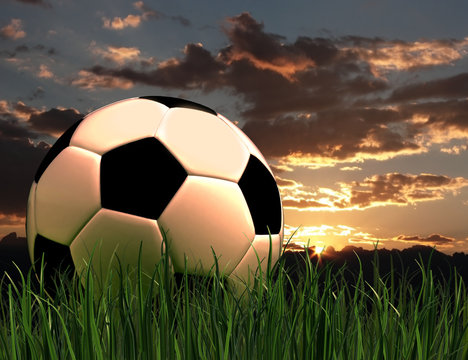 Pallone da calcio tra l'erba al tramonto