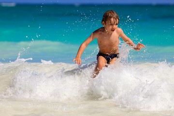 young boy enjoys playing on the waves in a tropical sea
