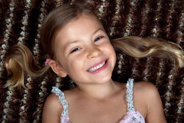 Pretty little girl lying down on a rug and smiling
