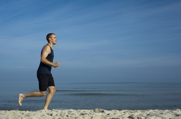 Młody mężczyzna uprawiający jogging na plaży - obrazy, fototapety, plakaty