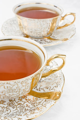 Two cup with tea from gold porcelain tea-set