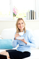 Obraz na płótnie Canvas Smiling businesswoman holding a cup of coffee sitting on a sofa