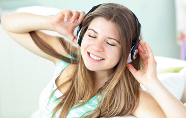 Naklejka premium Delighted woman listening to music with headphones on a sofa