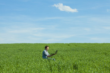 Naklejka na ściany i meble young man using laptop in the field