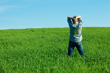 young man standing with a sunflower in the green field