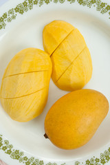Ripe golden mangoes on white dish