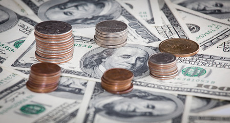 Fototapeta premium coins over hundred dollar bills background close up view