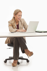 Young business girl sitting at desk with laptop