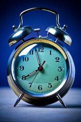 Old fashioned metal alarm clock on a blue background.