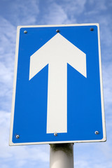 White one way traffic sign against blue sky background