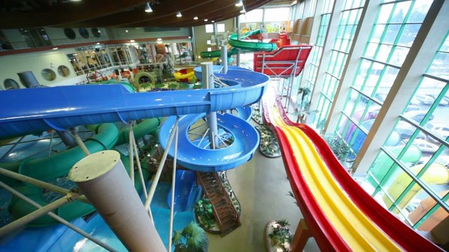 People rapidly slide down plastic hills in large water park