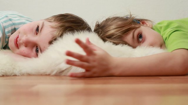 boy and girl  lie on floor on shaggy shawl and are kept in hands