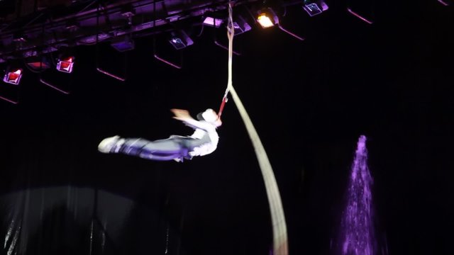 Agile acrobat rapidly spins on tethers in air in circus