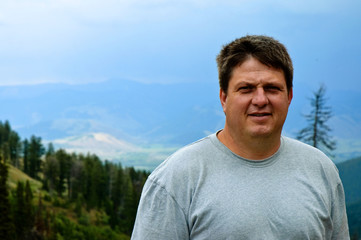 Ordinary guy outdoors with mountains and trees in background