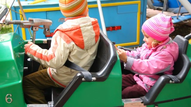 boy and little girl sits in dodgem in city park amusement
