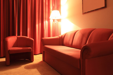 Hotel interior with red couch, armchair and floor lamp