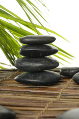 Stacked pebbles with palm leaf on mat