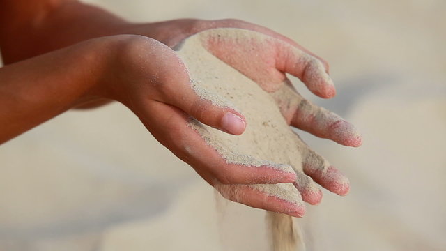 Human hands strewing sand through fingers