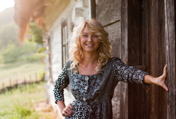 Beautiful blond woman near country house in the sunset