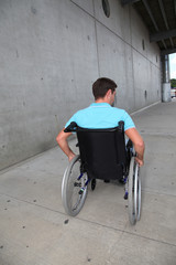 Fototapeta na wymiar Young man using wheelchair in town