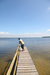 Fototapeta na wymiar Man on a pontoon by a lake in summer
