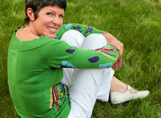 femme de 50 ans assise dans l'herbe