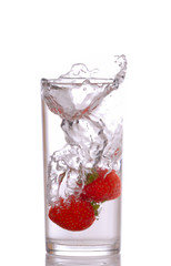 Strawberries splashing in glass of water