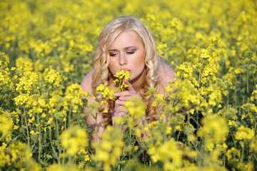 Naklejka na ściany i meble Beautiful young blonde woman in a field of wildflowers.