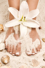 weisse blüte zwischen zarten füßen einer Frau im Sand © schwede-photodesign