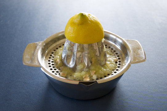 Zitronenpresse mit einer halben Zitrone und ausgepresstem Saft