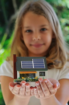 Fillette présentant une maison à énergie positive.