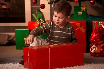 Obraz na płótnie Canvas Little boy wrapping out christmas present