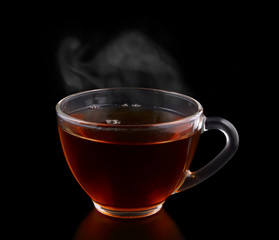 Glass cup of tea with vapor isolated on black