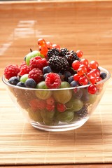 Fruit mix in the glass container, on a table from straw