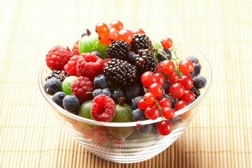 Fruit mix in the glass container, on a table from straw