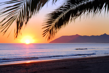 Obraz na płótnie Canvas Zachód słońca nad morzem z sylwetką dłoni