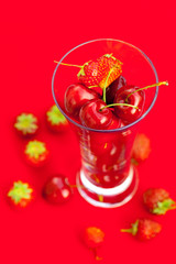 glass of cherry and strawberry on a red background