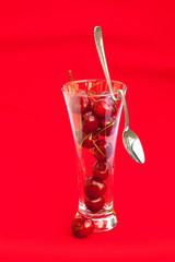 glass of cherry and spoon on a red background
