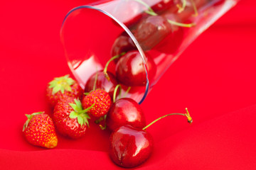 glass of cherry and strawberry on a red background