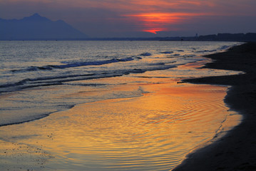 tramonto riflesso sulla riva del mare