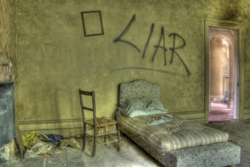 HDR photo of bed in derelict house. Grafitti against wall