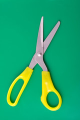 Yellow scissors on green background