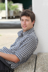 Young man sitting on the ground with mobile phone