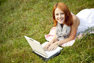 Young fashion girl with notebook lying at green grass