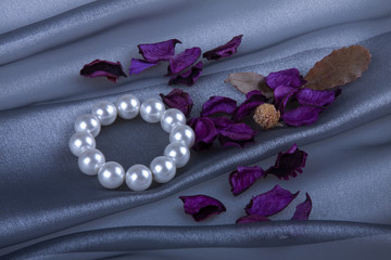 Obraz premium Жемчужный браслет и саше на фоне серебряной органзы