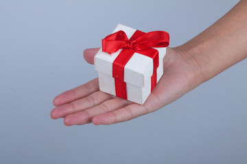 Женская рука протягивает коробку с подарком