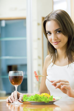 Young smiling woman with salad and redwine at home