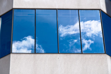 The sky reflected on a window at the facade of a building