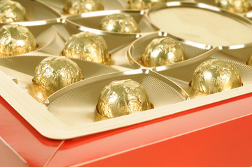 Chocolate candies wrapped in golden paper in a gift box