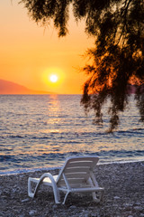 Chair on beach at sunset